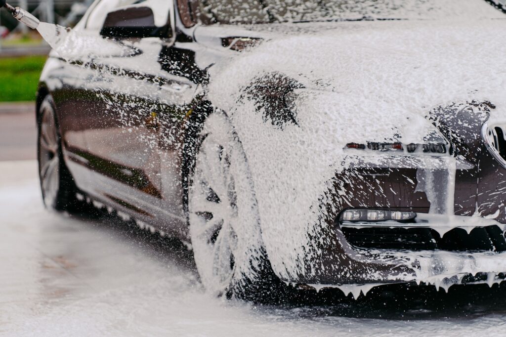 Chemical detergent for cleaning auto. Car in white foam. Washing vehicle. Carwash
